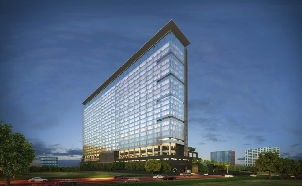 Tall glass skyscraper exterior at dusk with highway view in commercial office space for sale Hyderabad